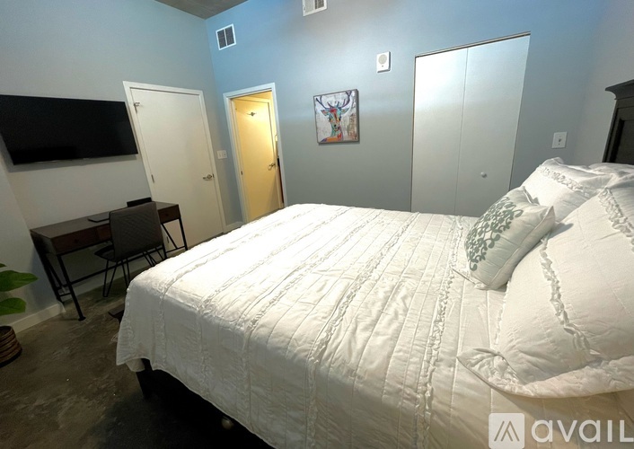 A bedroom with a large bed and a TV on the wall.