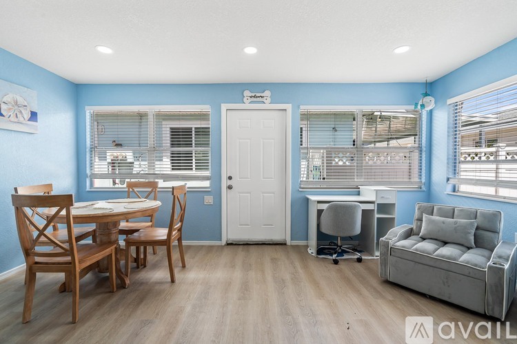 A room with a dining table and chairs, a couch, and a desk with a chair.