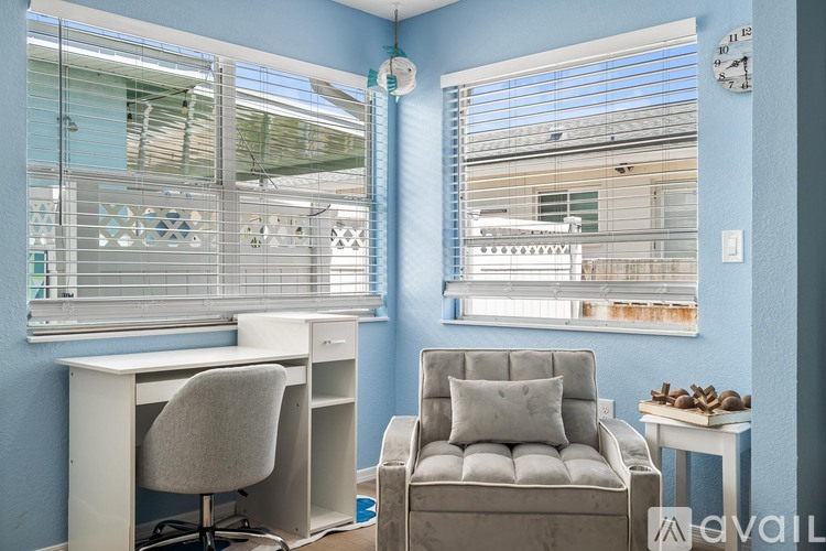 A room with a desk, chair, and window with blinds.