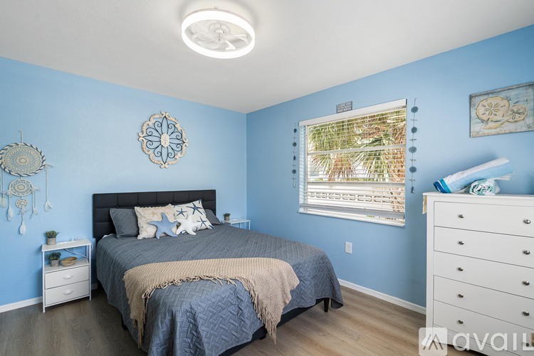 A bedroom with blue walls and a large bed with a grey comforter.