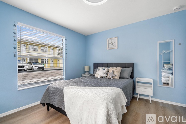 A bedroom with a bed, nightstand, and window with blinds.