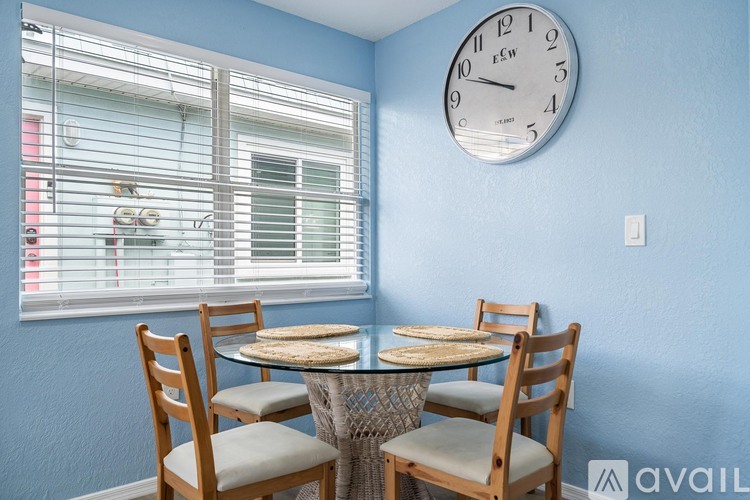 A dining room with a table set for four and a clock on the wall.