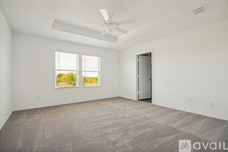 A spacious room with a ceiling fan and two windows.