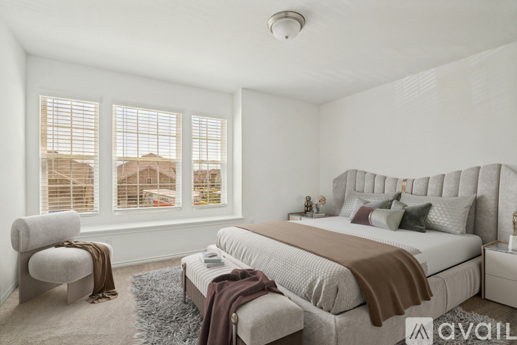 A bedroom with a large bed and a chair by the window.