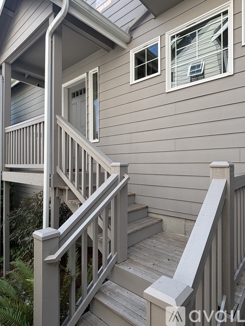 A wooden staircase with a railing leads up to a door on a house.