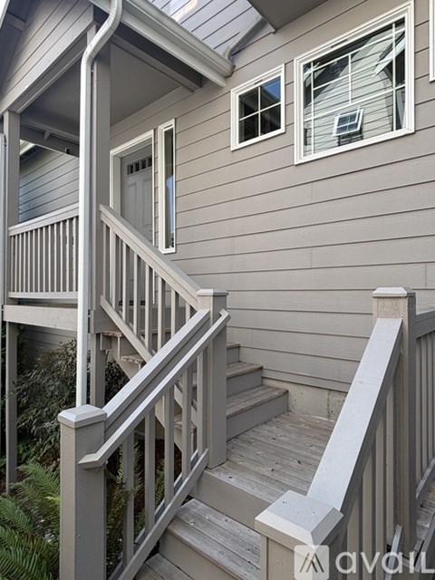 A wooden staircase with a railing leads up to a door on a house.