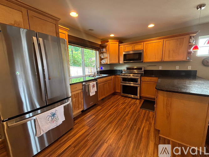 A kitchen with wooden floors and a stainless steel refrigerator.