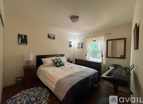 A bedroom with a bed, a piano, and pictures on the wall.