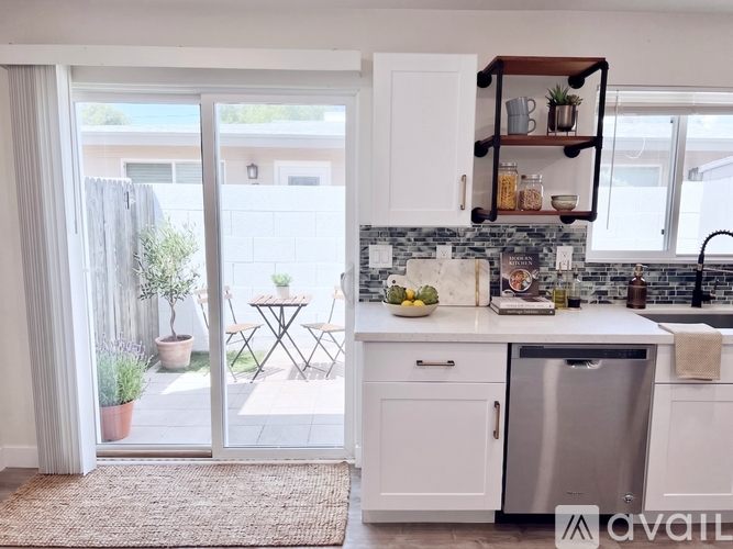 A kitchen with a stainless steel dishwasher and a countertop with a bowl of fruit on it.