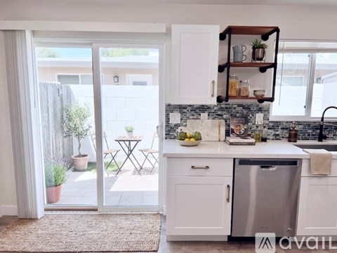 A kitchen with a stainless steel dishwasher and a countertop with a bowl of fruit on it.