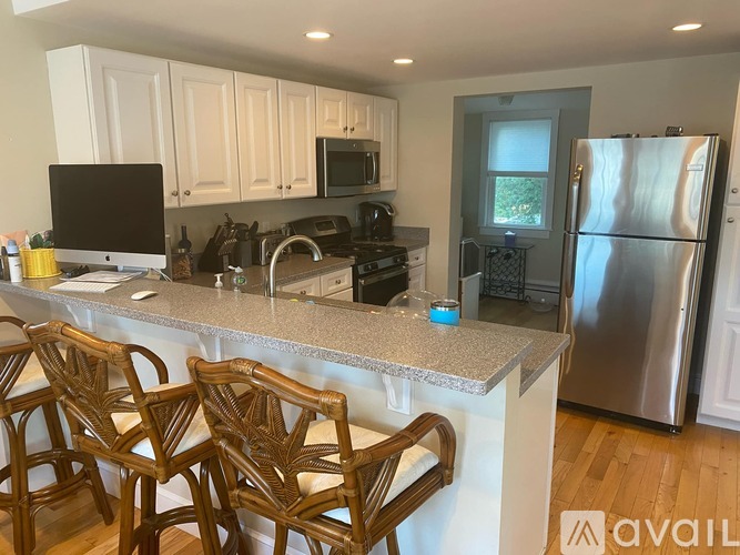 A kitchen with a granite countertop and wooden chairs.