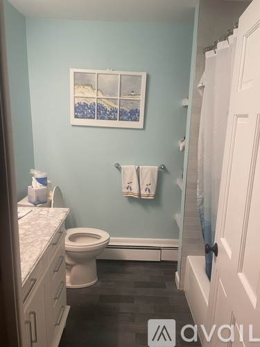 A bathroom with a toilet, a sink and a painting on the wall.