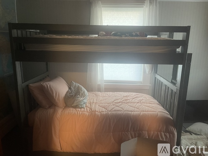 A bed with a quilted bedspread and two pillows is in a room with a window.