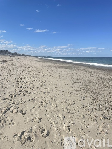 A beach with footprints in the sand leading to the water.