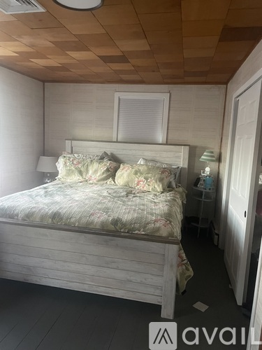 A bedroom with a bed, nightstand, and lamp.
