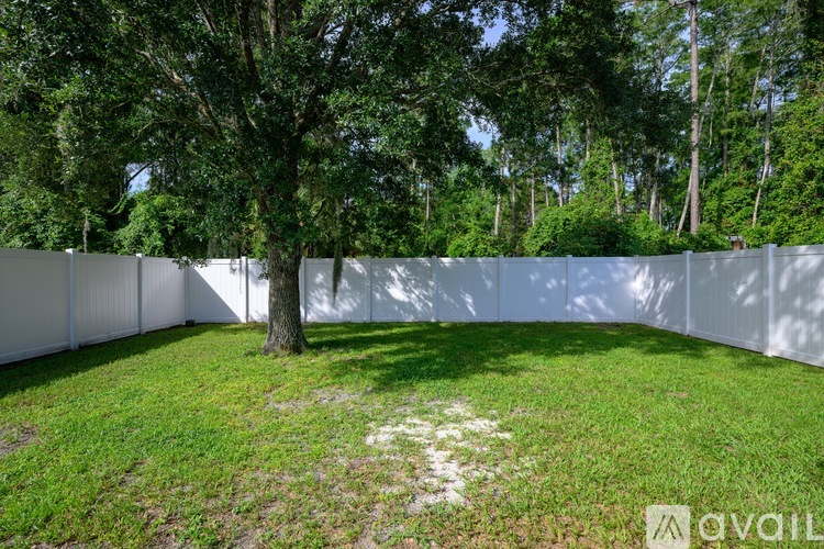 A white fence encloses a grassy area with a tree.