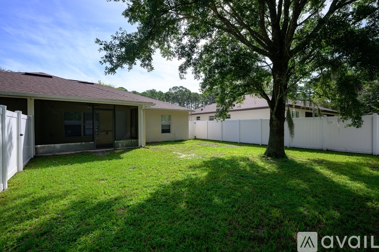 A backyard with a tree and a house in the background.