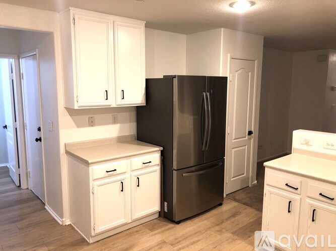 A kitchen with white cabinets and a black refrigerator.