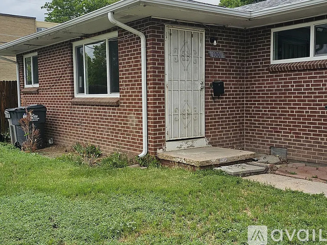 A red brick house with a white door and a mailbox on the right side.
