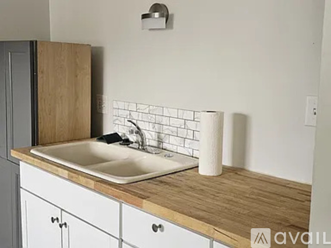 A kitchen counter with a sink and a roll of paper towels on it.