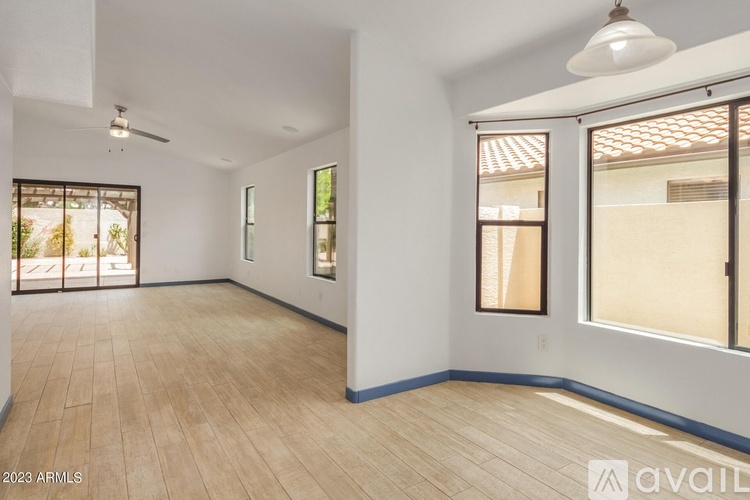 A spacious room with wooden flooring and large windows.