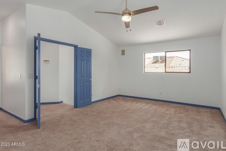 A room with a ceiling fan and a window with a view of a building.