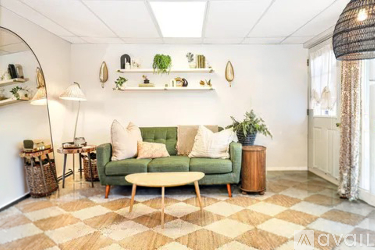 A living room with a green couch, a round table, and a checkered floor.