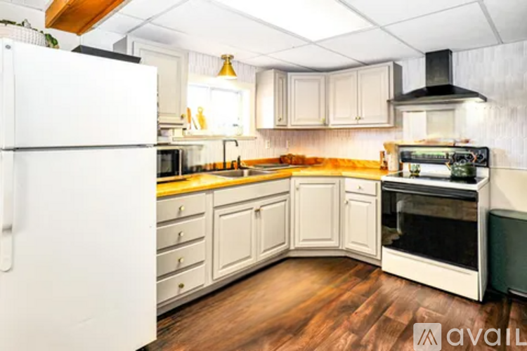 A kitchen with white appliances and wooden floors.