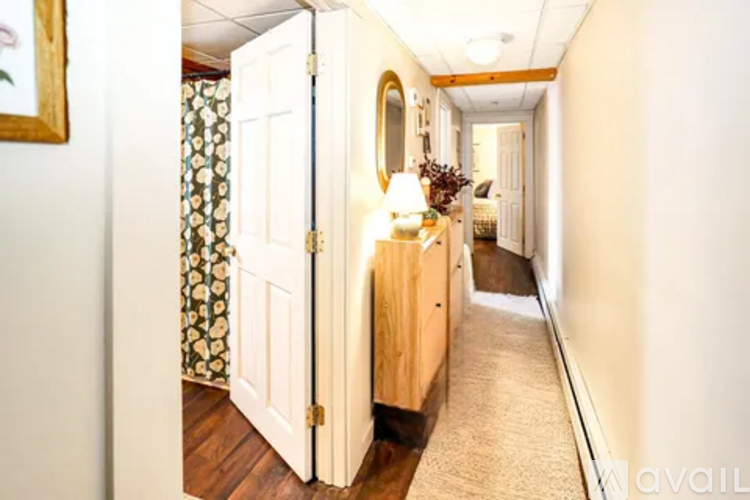 A hallway with a carpeted floor and a door on the left.