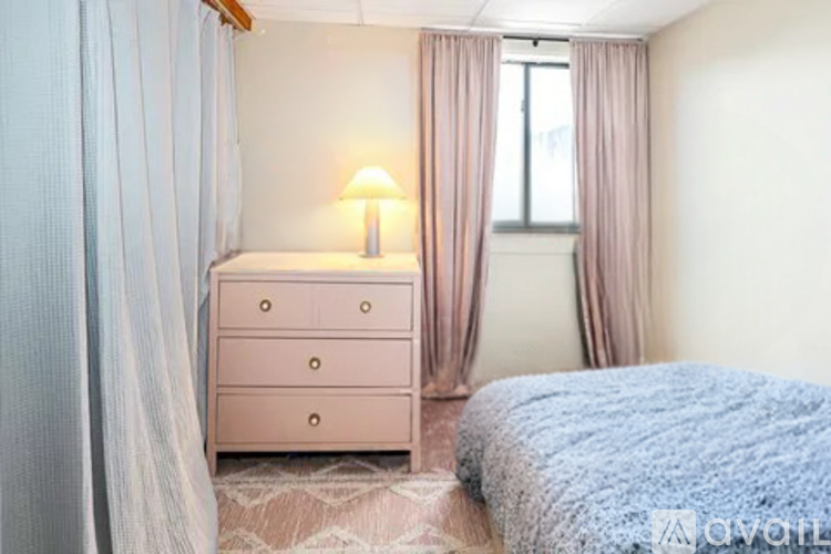 A bedroom with a pink dresser and a blue bedspread.