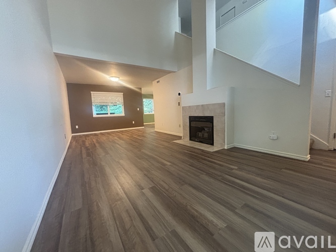A spacious room with wooden flooring and a fireplace.
