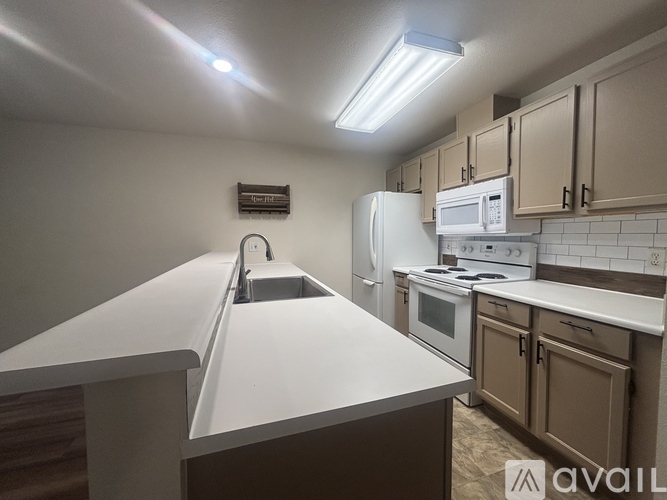 A kitchen with white appliances and brown cabinets.