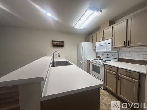 A kitchen with white appliances and brown cabinets.