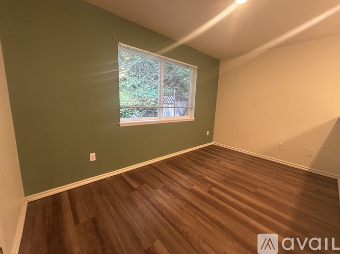 A room with a window and wooden flooring.