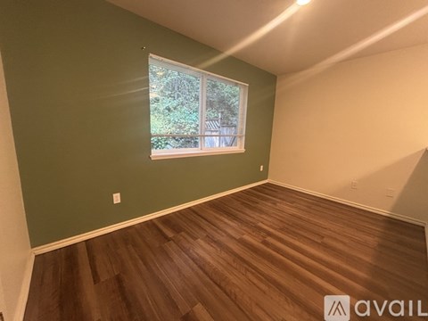 A room with a window and wooden flooring.