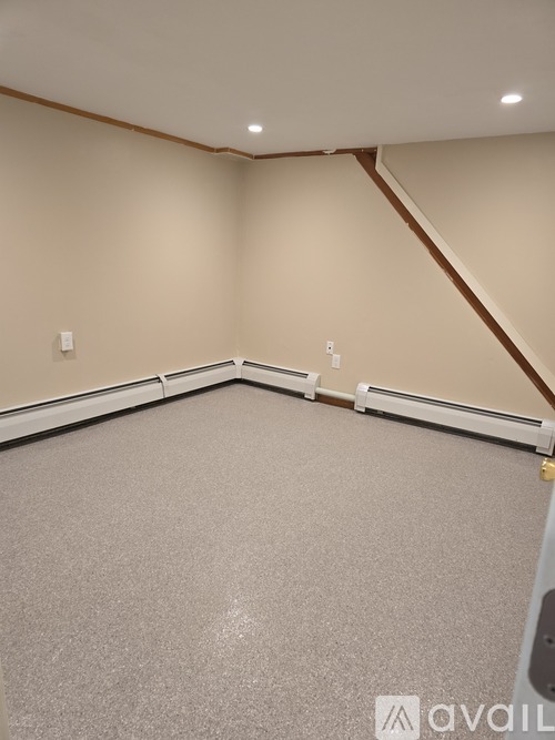 A room with a carpeted floor and a corner where the wall meets the ceiling.
