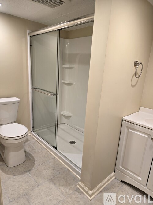 A bathroom with a toilet, a shower with a glass door, and a towel rack.