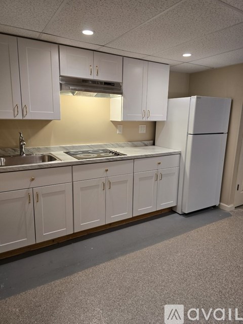 A kitchen with white cabinets and a white refrigerator.