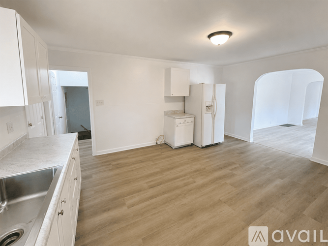 A kitchen with white cabinets and a wooden floor.