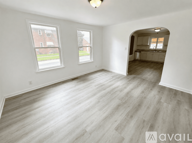 A spacious room with light wood flooring and white walls.