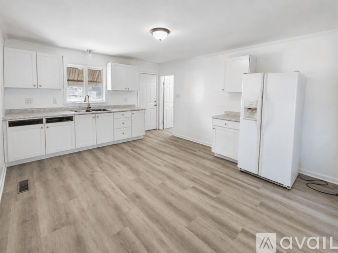 A kitchen with white cabinets and a wooden floor.