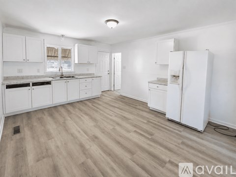 A kitchen with white cabinets and a wooden floor.