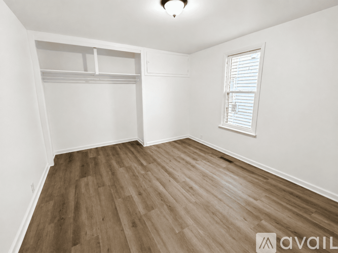 A room with wooden flooring and a window with blinds.