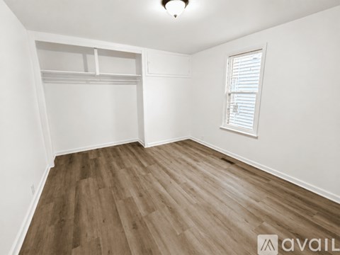 A room with wooden flooring and a window with blinds.