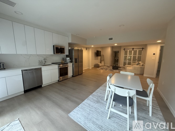 A kitchen with white cabinets and a dining table with four chairs.