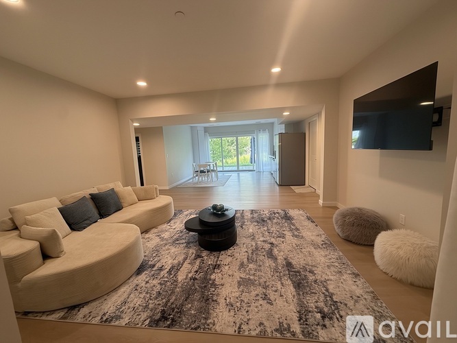 A modern living room with a large rug and a curved sofa.