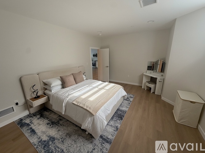 A bedroom with a large bed and a rug on the floor.