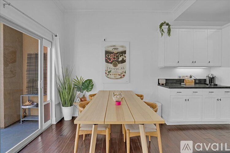 A dining room with a wooden table and chairs, a plant, and a framed picture on the wall.
