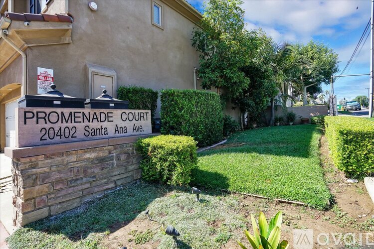 A building with a sign that says Promenade Court 20402 Santa Ana Ave.