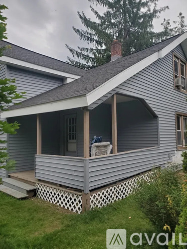 A house with a grey siding and a white porch.